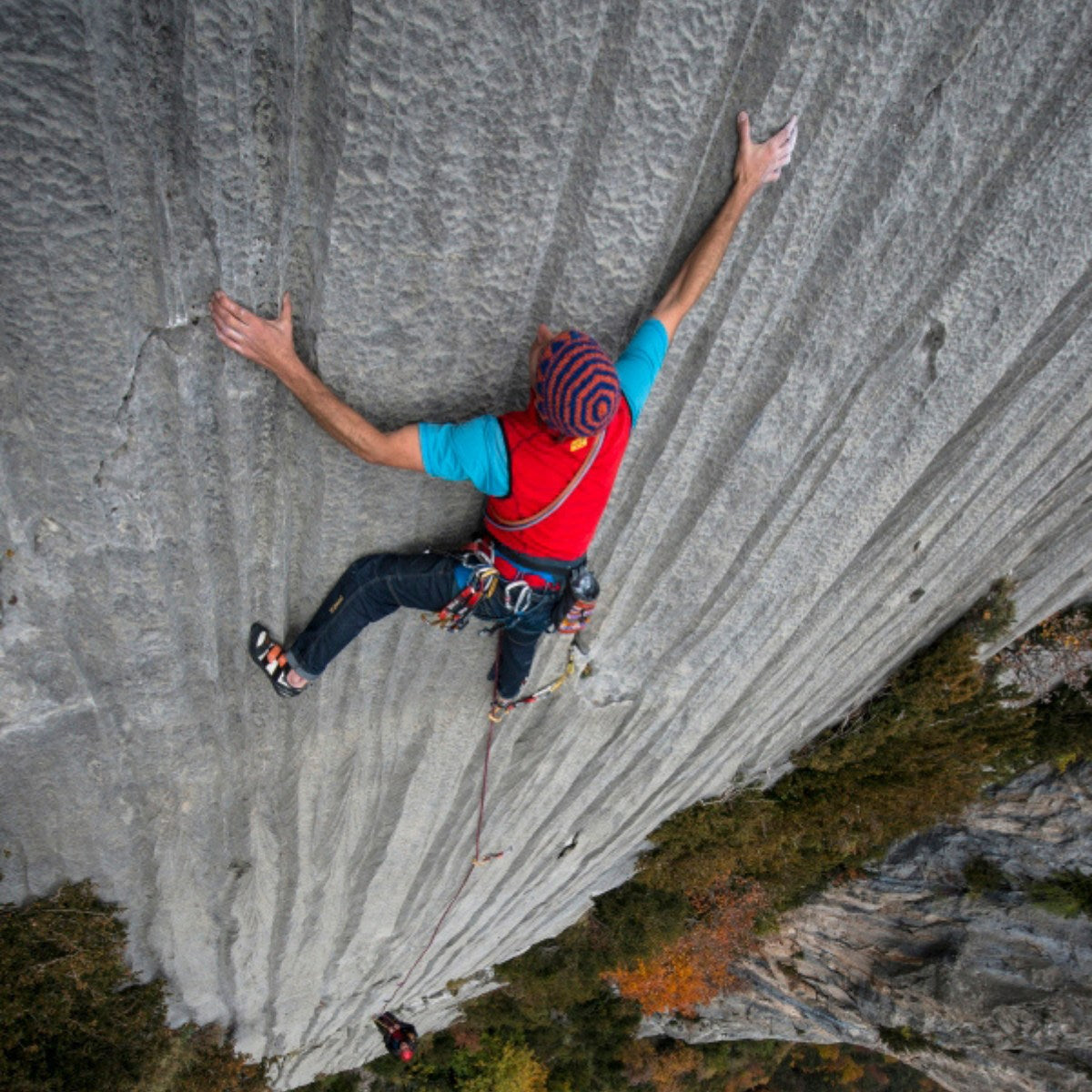 Person rock climbing on a steep cliff face with a scenic background Rock climber applying Monkey Skin ayurvedic hand recovery wax to chalked and calloused hands after a tough climb